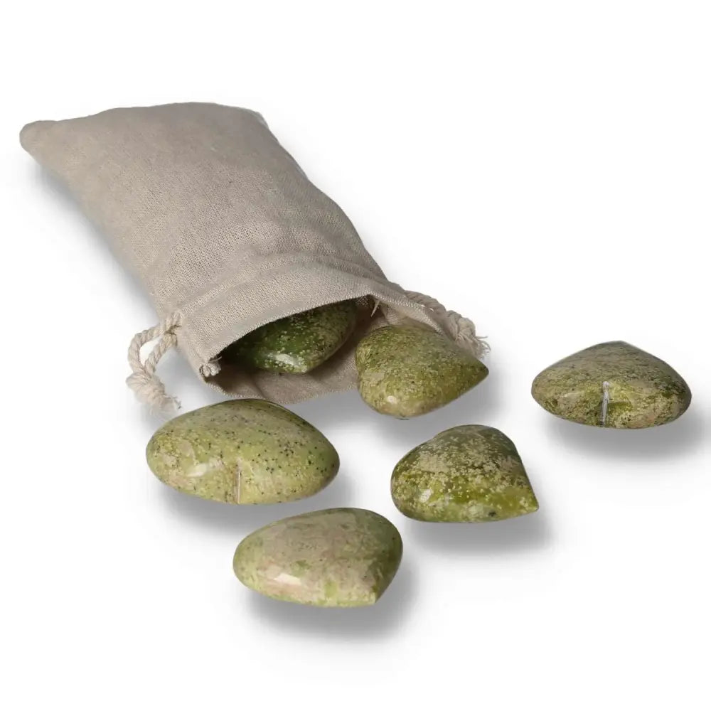 Small serpentine heart crystals with earthy green tones, partially spilling from a natural fabric pouch.