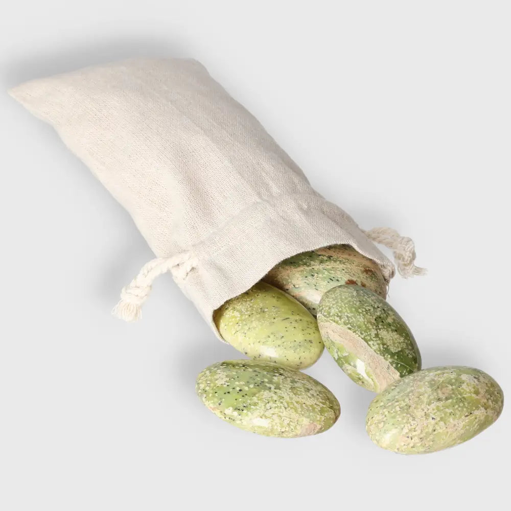 Small Serpentine Palm Stones spilling from a linen bag, showcasing vibrant green hues and smooth polished surfaces.