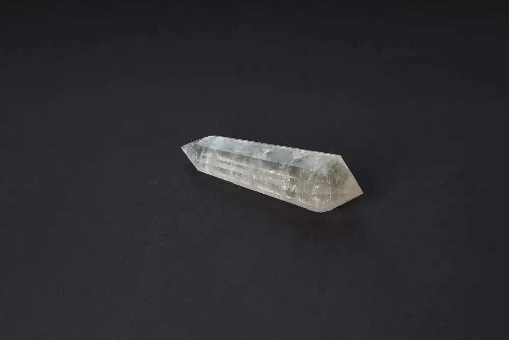 Polished smoky quartz point with translucent brown tones for grounding and protection on a dark background.