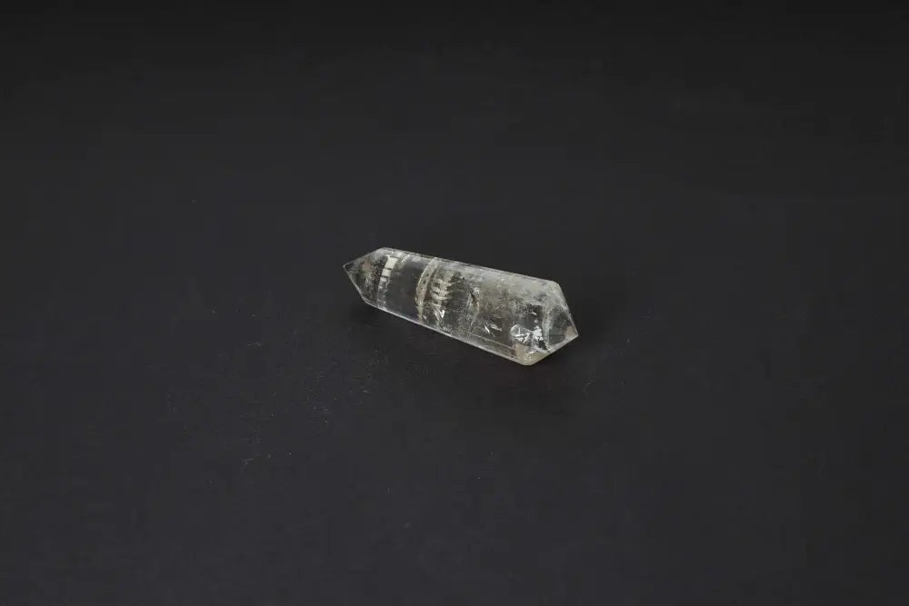 Smoky Quartz Point with translucent tones, offering grounding clarity and protective energy, against a dark background.