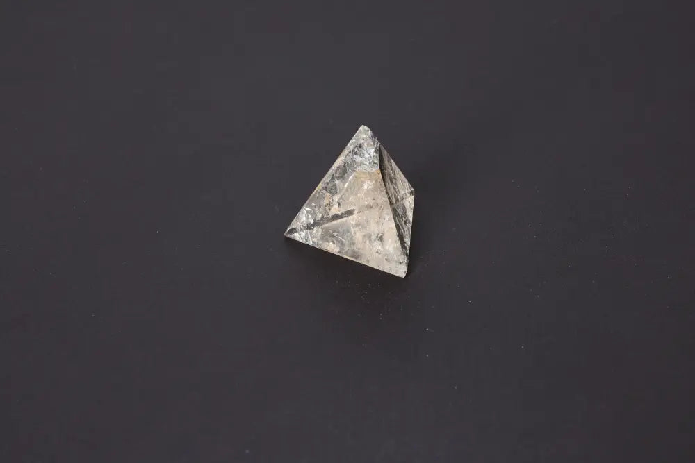 Smoky Quartz Pyramid 5 cm on dark surface, showcasing grounding energy and translucent gray to brown hues for stability and protection.