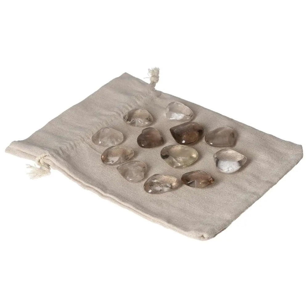 Assorted smoky quartz hearts on a beige drawstring pouch, ideal for decision-making and practical thinking enhancement.