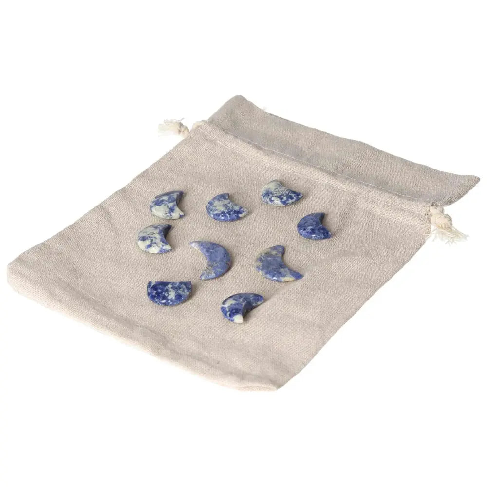 Sodalite small crescent moon stones with white marbling on a beige pouch, symbolizing intuition and emotional balance.