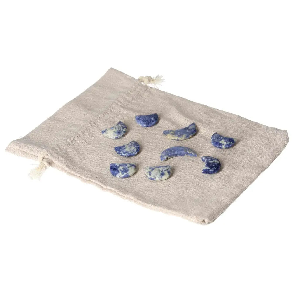 Sodalite small crescent moons on a beige cloth, symbolizing intuition and calm with indigo tones and white marbling.