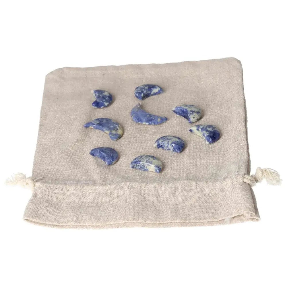 Small sodalite crescent moons on fabric, symbolizing intuition and emotional balance, with deep indigo hues and white marbling.