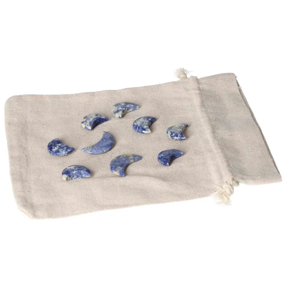 Nine small sodalite moon carvings on a beige cloth bag, showcasing deep indigo and white marbling for intuition and emotional balance.