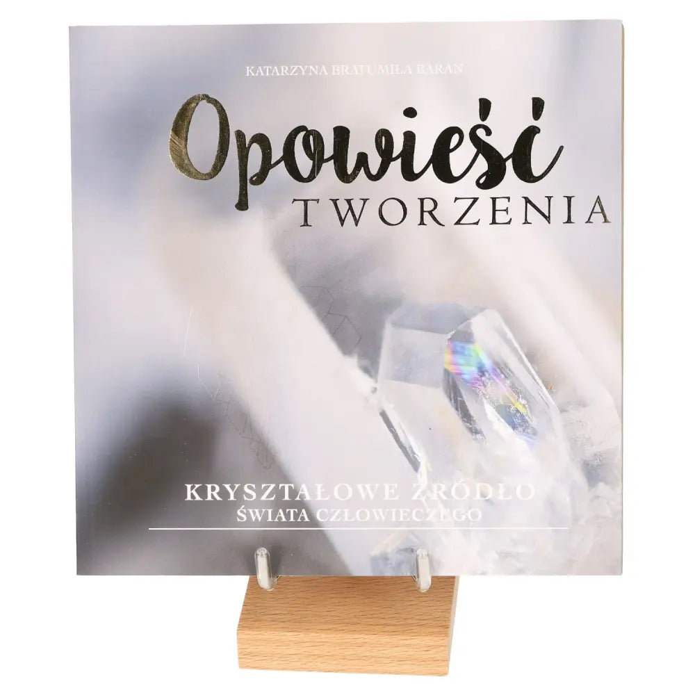 Book titled 'Opowieść Tworzenia' featuring crystals, symbolizing the harmony between heart and mind on a wooden stand.