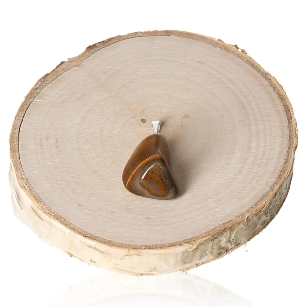 Elegant Tigers Eye Tumbled Pendant on wood, showcasing golden and brown bands, highlighting its captivating and grounding qualities.