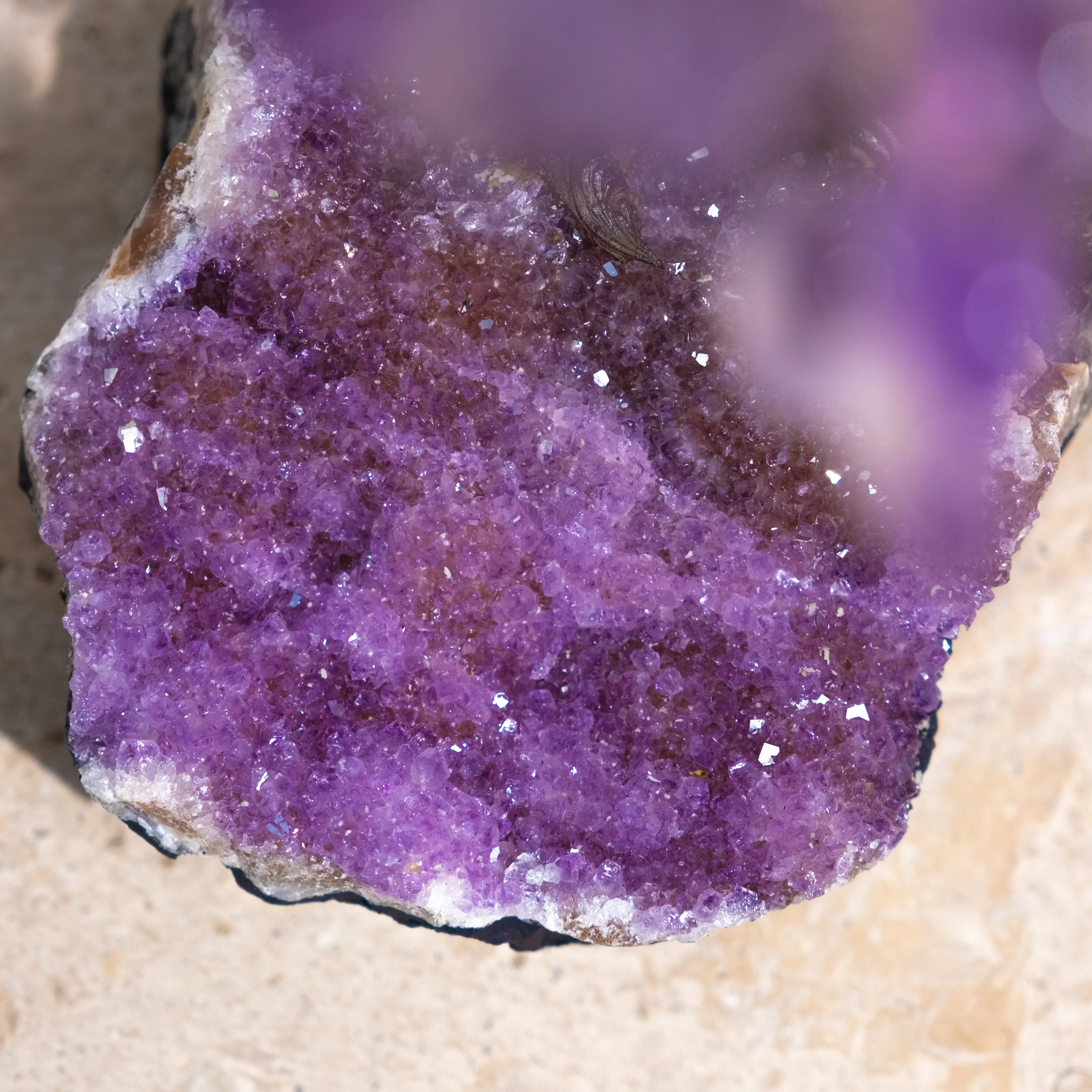 Close-up of a natural amethyst crystal with vibrant purple hues, showcasing its raw and sparkling surface texture.