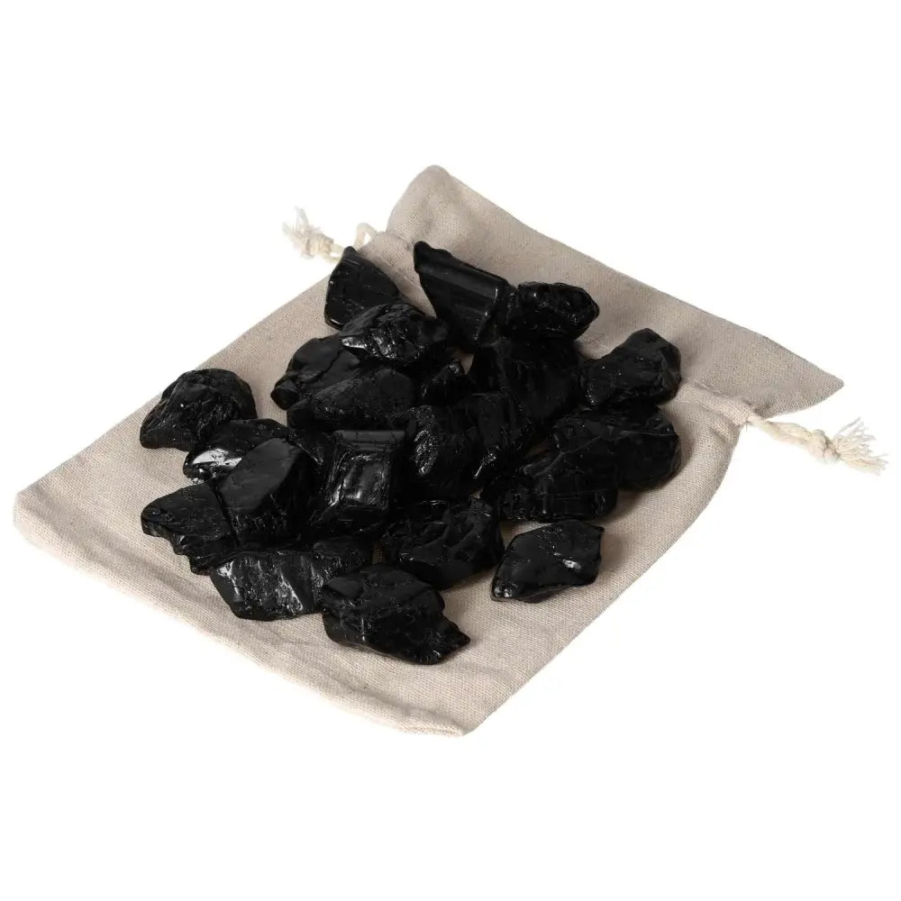 Tumbled black tourmaline stones on a fabric pouch, ideal for cleansing and transforming negative energy.