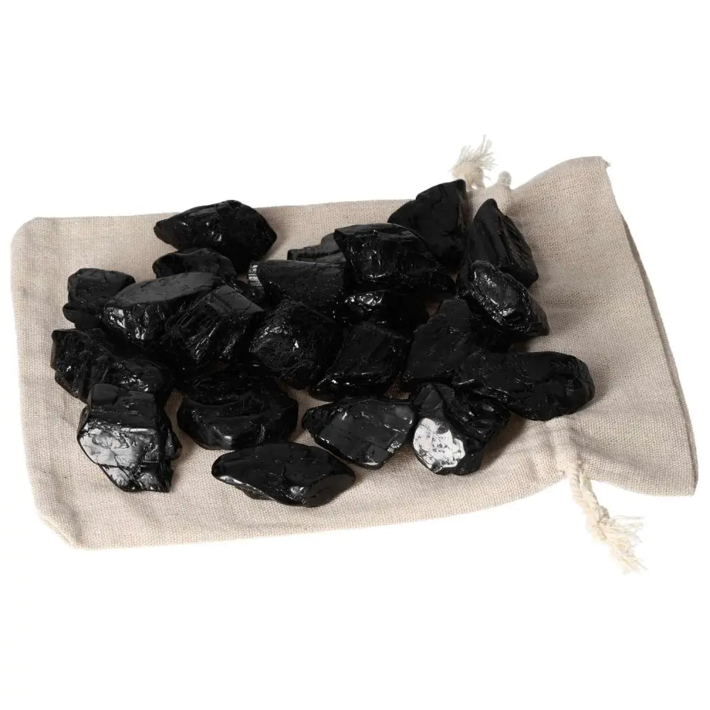 Tumbled Black Tourmaline L stones on beige pouch for energy cleanse and grounding.