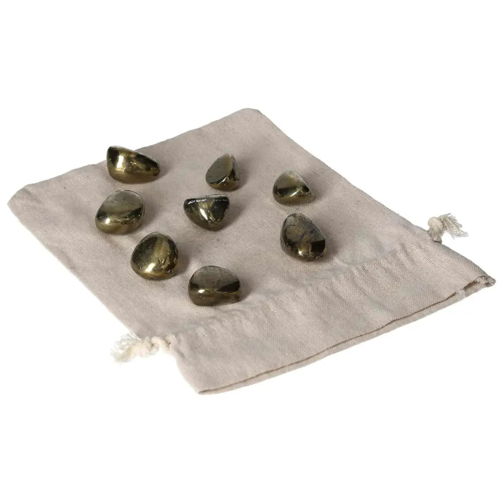 Collection of tumbled Chalcopyrite crystals on a beige pouch, known for enhancing psychic abilities and promoting positive thinking.