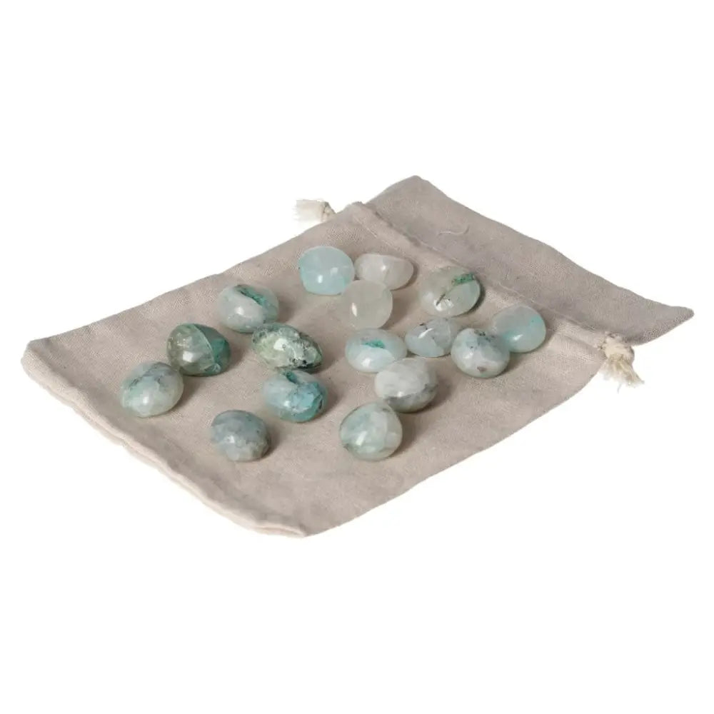 Tumbled Chrysocolla stones on beige pouch, enhancing speech and feminine energy.