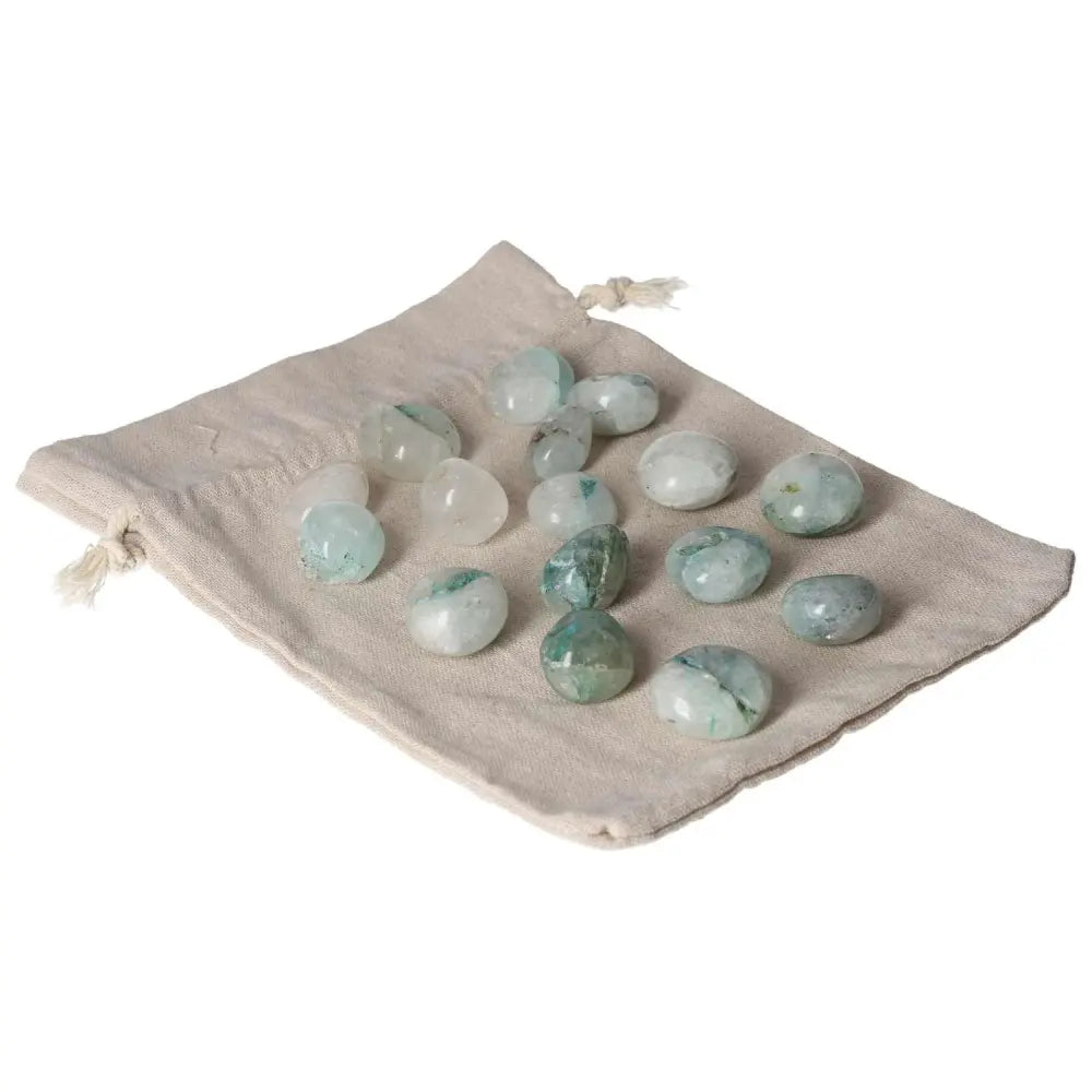Tumbled chrysocolla stones on a beige cloth bag, known for enhancing communication and understanding emotions, especially for women.