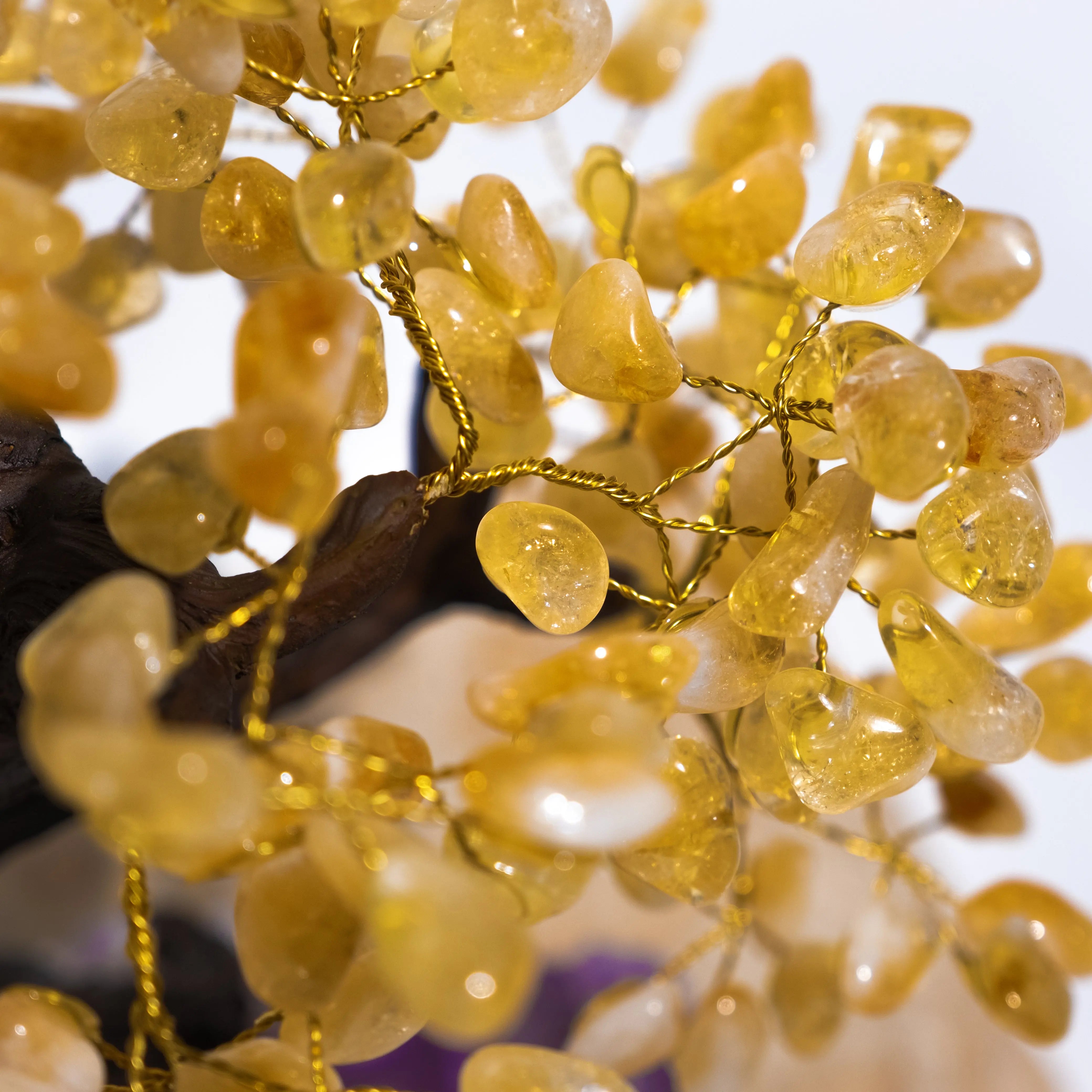 Close-up of citrine crystal bonsai tree with tumbled gemstones, symbolizing prosperity and positive energy.
