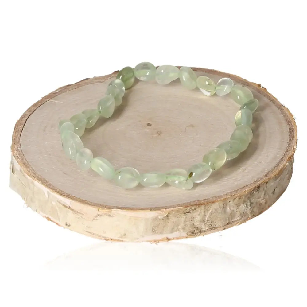 Tumbled Prehnite Bracelet displayed on a wooden surface, showcasing its soft green stones known for enhancing intuition and tranquility.