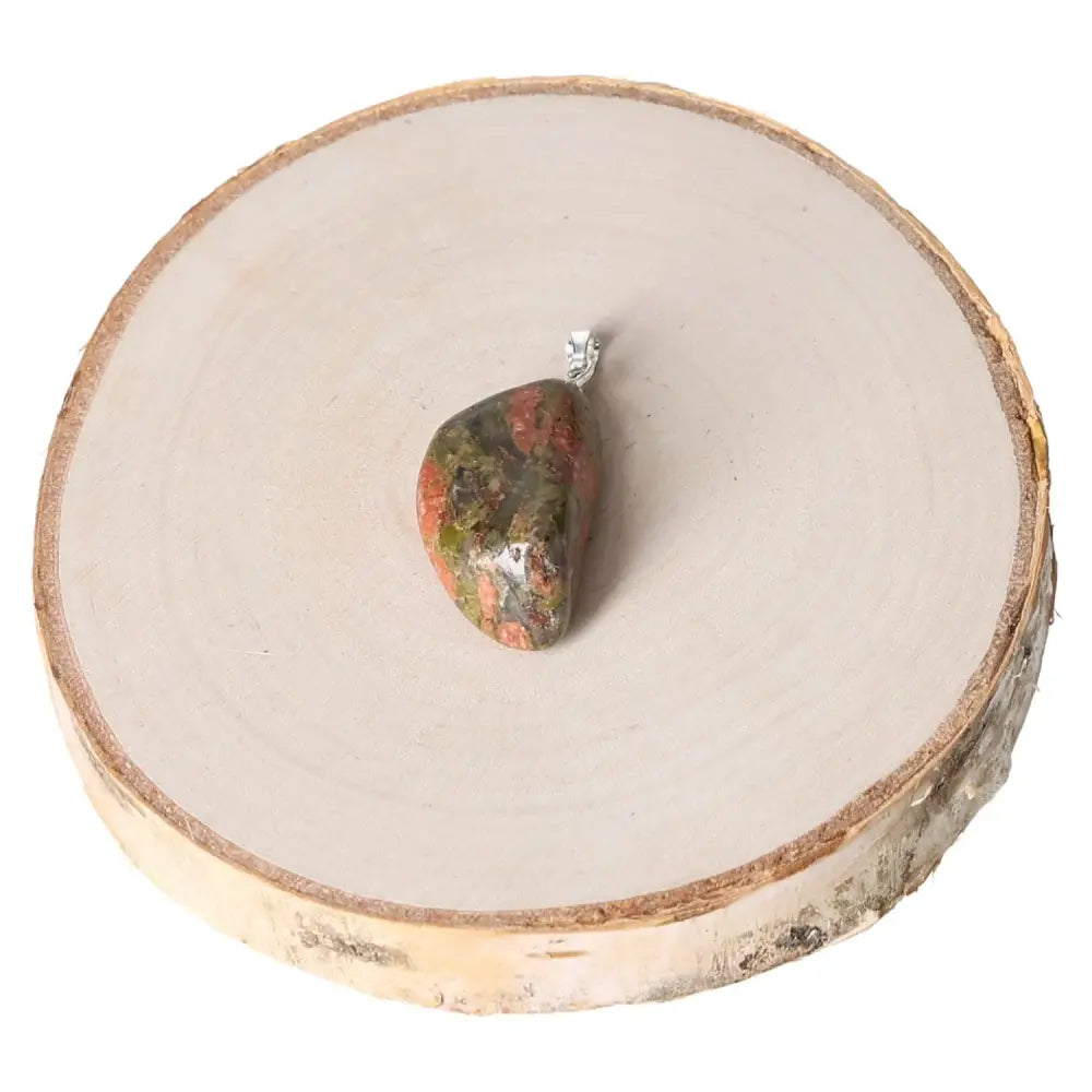 Unakite Tumbled Pendant on wooden platform, showcasing unique olive green and pink hues, ideal for spiritual balance and jewelry collectors.