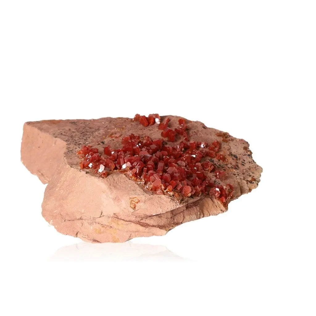 Vanadinite Druze with vibrant red crystals, known for enhancing focus and creativity, displayed on rock surface.