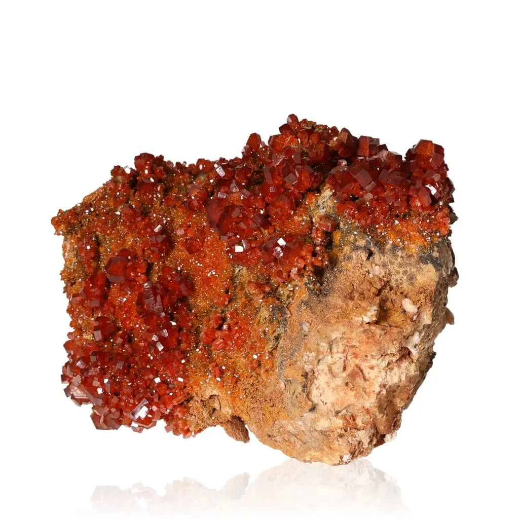 Vibrant red-orange Vanadinite druzy crystal formation on rock, showcasing its striking and grounding properties for collectors and creatives.