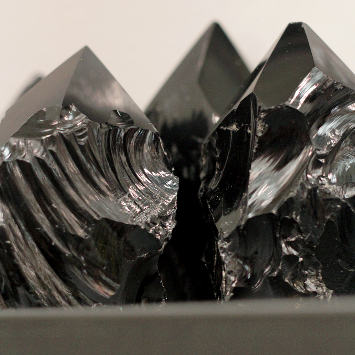 Shiny black obsidian on display stand showcasing its natural volcanic glass texture and sharp edges.