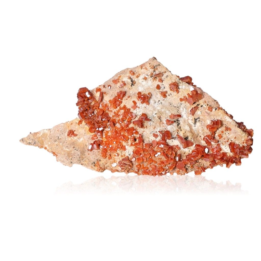 Vanadinite crystal with vibrant red-orange hexagonal formations on a beige rock surface, known for enhancing focus and creativity.