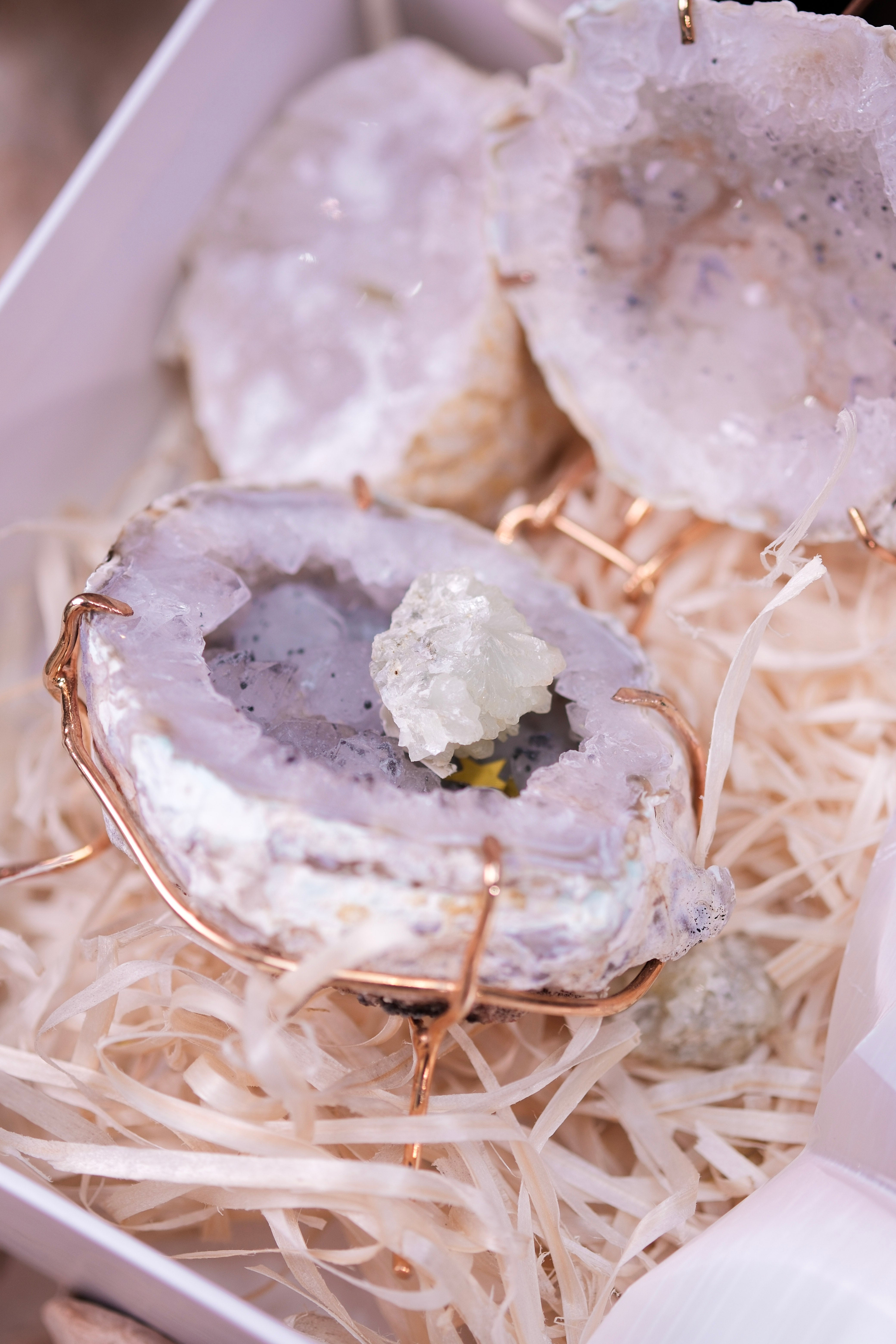 Close-up of decorative crystal geodes in a gift box with straw packaging, showcasing natural beauty and elegance.