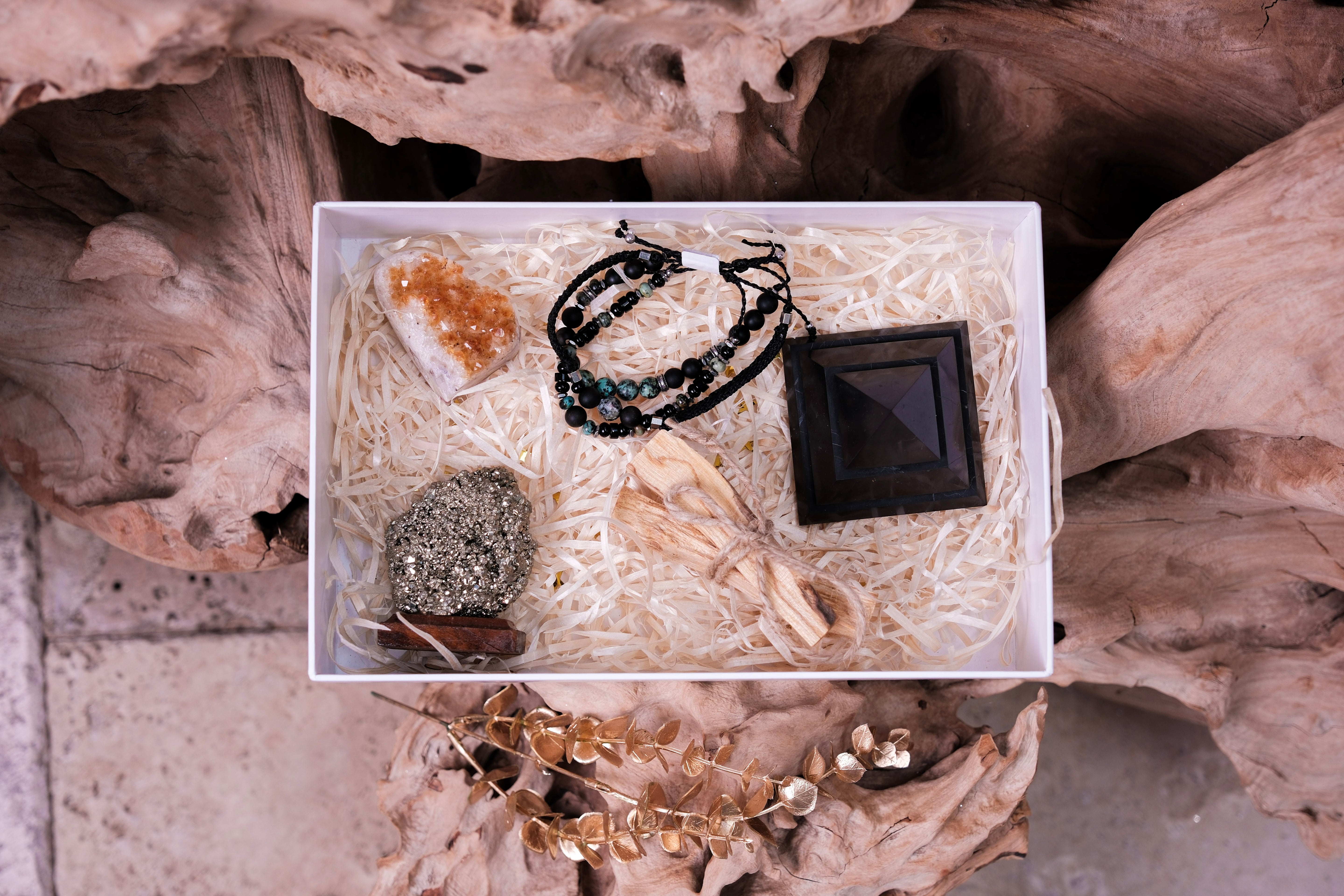 Luxury Christmas gift box with black Shungite pyramid, crystal treasures, and elegant bracelets on rustic wood background.