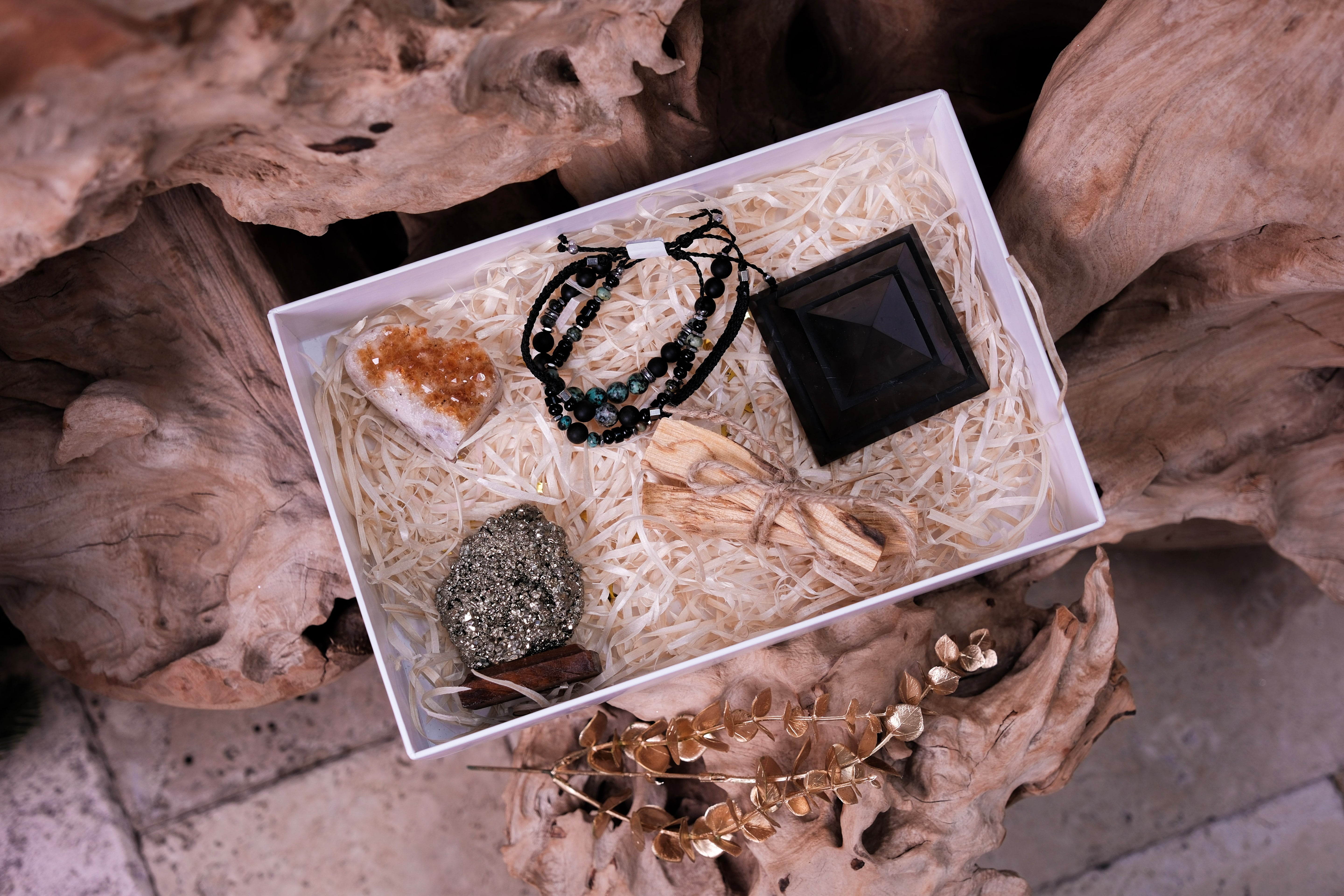 Christmas Luxury Crystal Gift Box with black shungite pyramid, bracelets, and crystals on natural wood background for holiday gifting