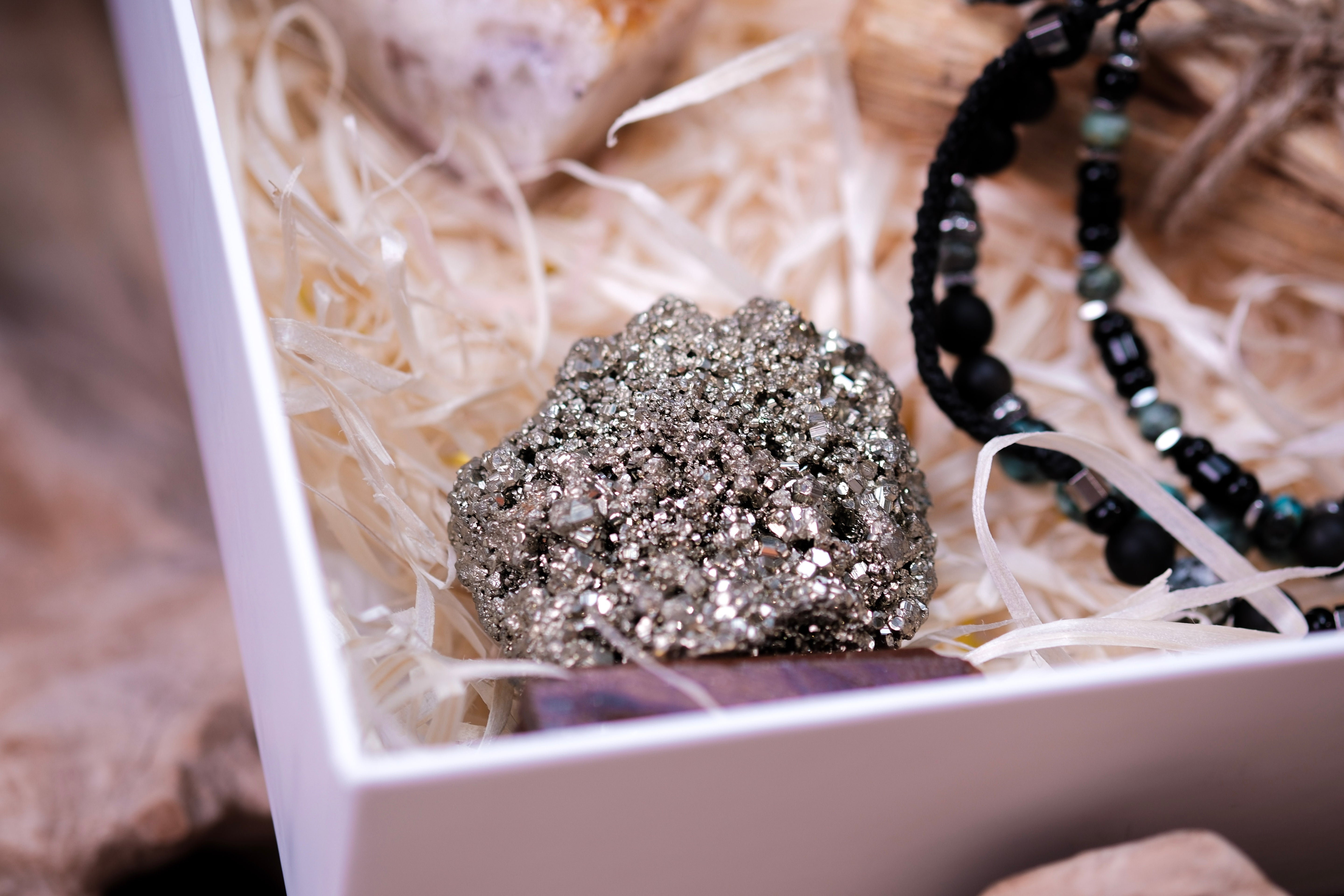 Luxury Christmas gift box with pyrite crystal and elegant beads on straw bedding.