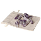 Amethyst Point S crystals from Sylvia Crystals on a beige drawstring pouch, symbolizing serenity, sophistication, and stress reduction.