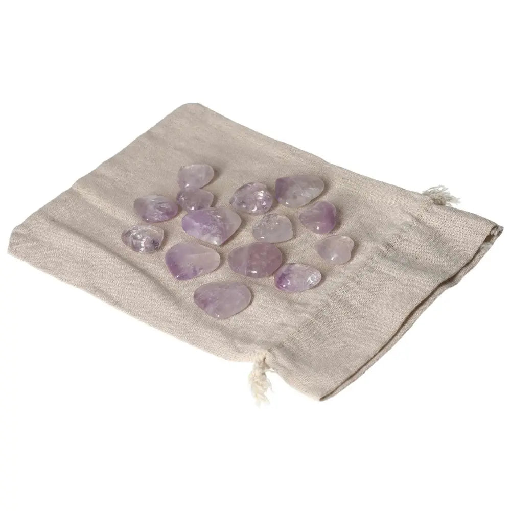 Assorted small amethyst heart stones on a beige drawstring pouch, known for reducing stress and enhancing emotional stability.