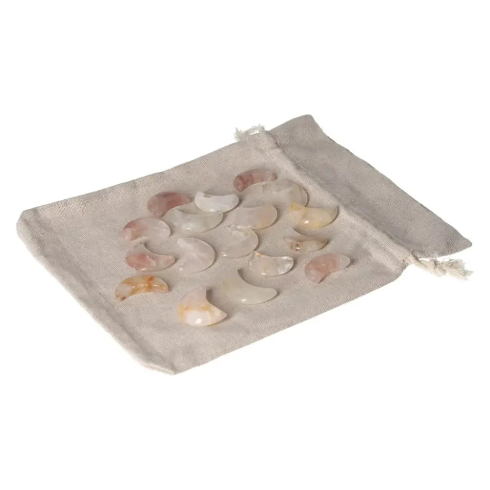 Golden Healer small moon stones spread on a beige fabric bag, showcasing their smooth texture and healing properties.