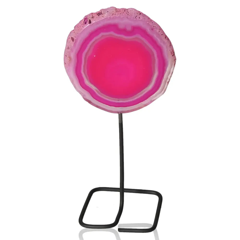 Vibrant pink agate slice on a metal stand, perfect centerpiece with calming properties, enhancing room's harmony and elegance.