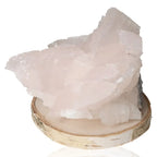 Soft pink Manganocalcite gemstone displayed on a wooden base, symbolizing emotional healing and forgiveness.