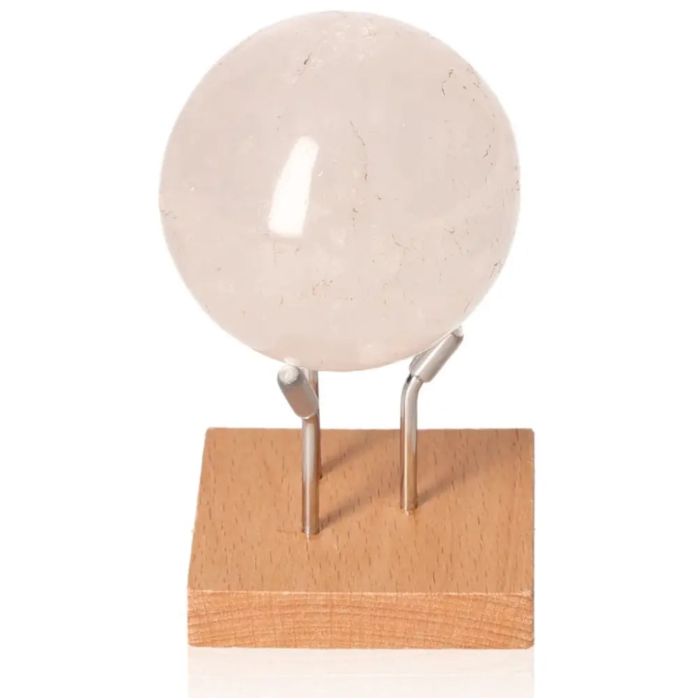 Rose Quartz Sphere by Sylvia Crystals, symbolizing love and peace, ideal for meditation, on a wooden stand for home decor.