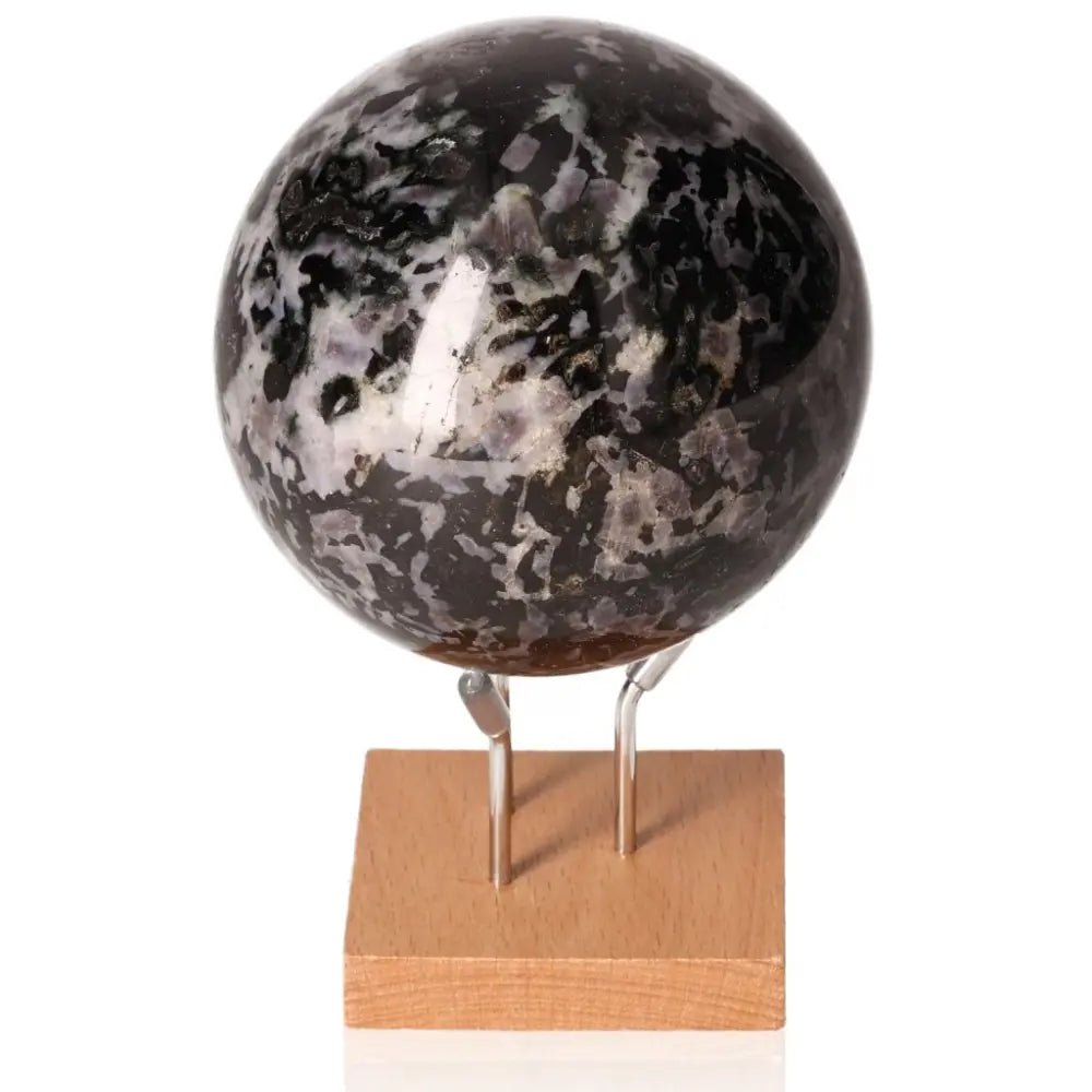 Indigo Gabbro sphere on stand, known as Mystic Merlinite, enhances intuition and spiritual growth with swirling black and indigo patterns.