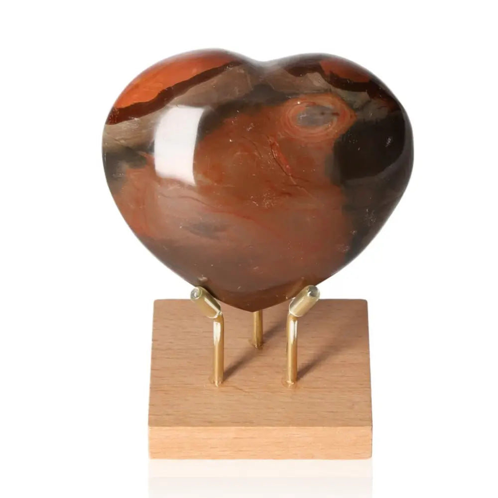 Polychrome Jasper Heart gem with rich colors, displayed on a wooden stand, showcasing natural elegance and vibrant palette.
