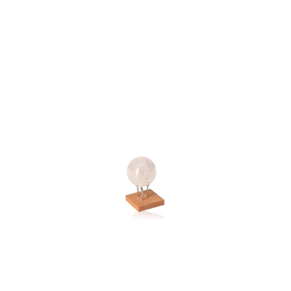 Clear crystal sphere on a wooden stand, symbolizing purity and spiritual energy.