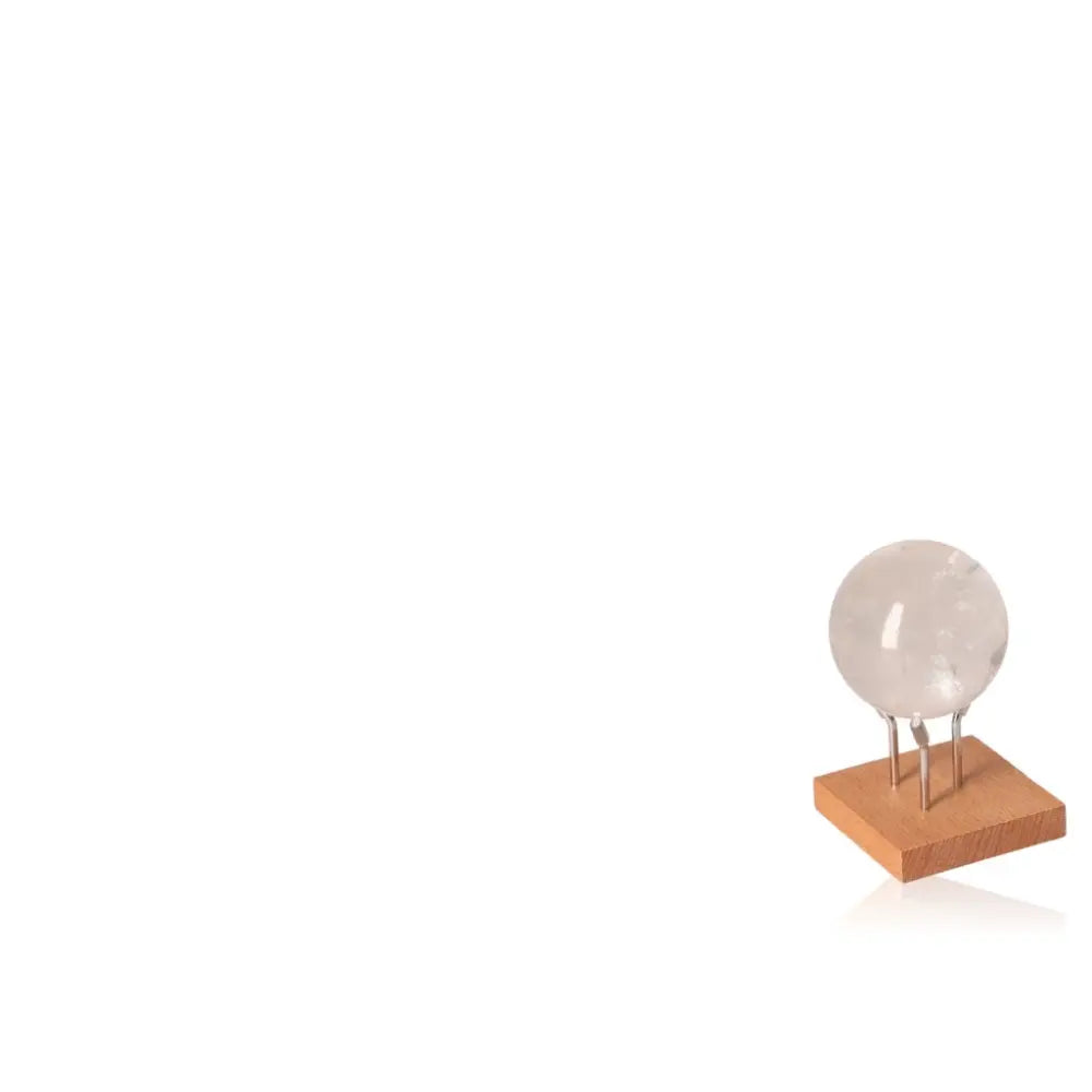 Lemurian Quartz Sphere on wooden stand, offered by Sylvia Crystals, showcasing its clarity and elegance.