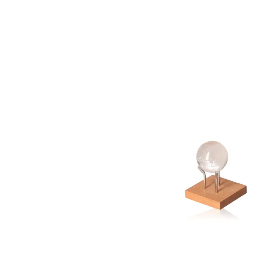 Clear crystal sphere on wooden base with metal stand, minimalistic design.