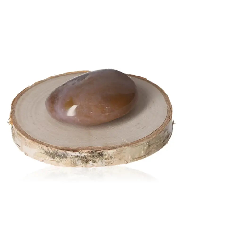 Banded Agate tumbled stone on a wood slice, showcasing its smooth surface and natural bands, ideal for energy balance and tranquility.