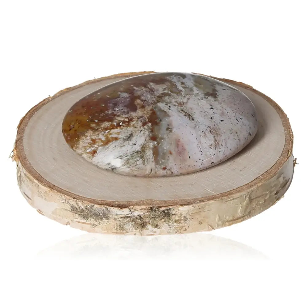 Tumbled Jasper gemstone on wood slice showcasing unique earthy swirls, polished for natural beauty and tranquility