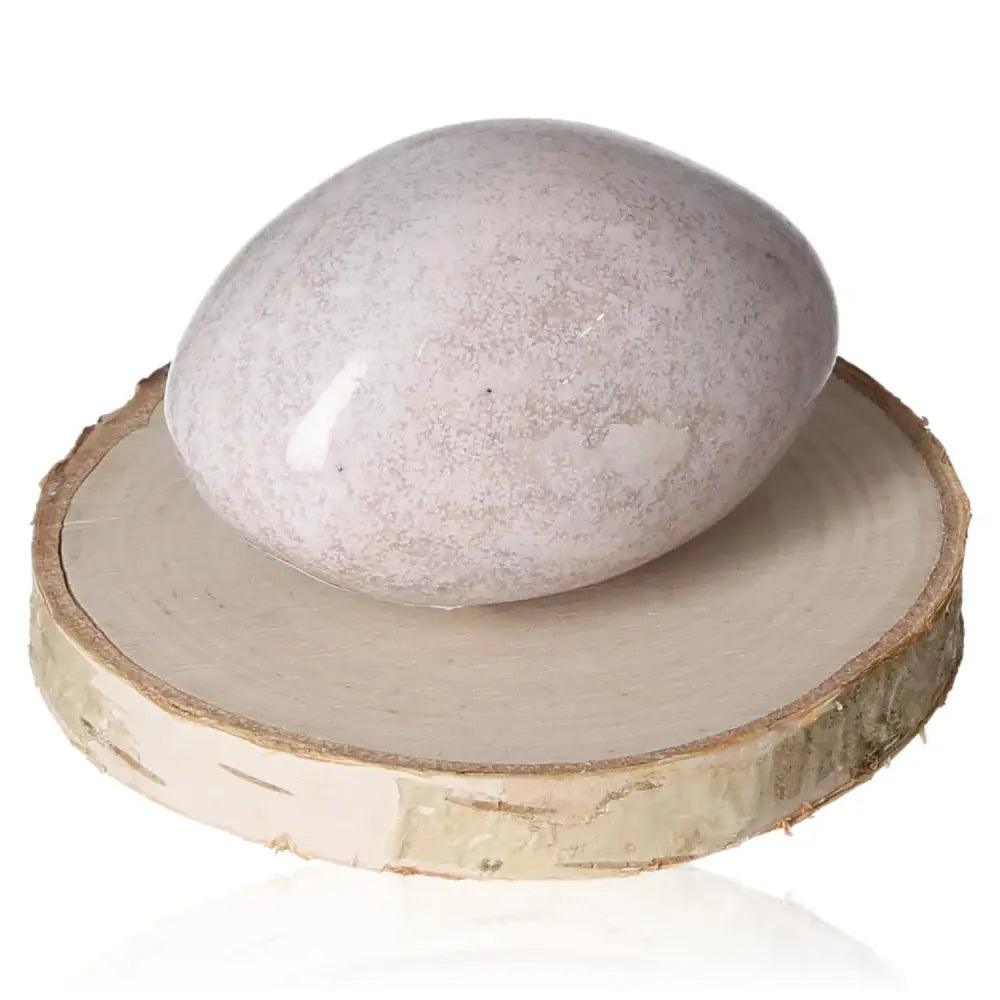 Smooth tumbled jasper stone on wooden slab promoting calmness and serenity