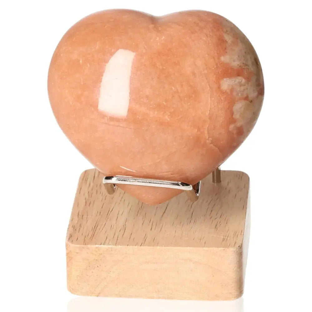 Peach Moonstone Heart for emotional balance and intuition support, placed on wooden stand. Ideal for protection and restful sleep.