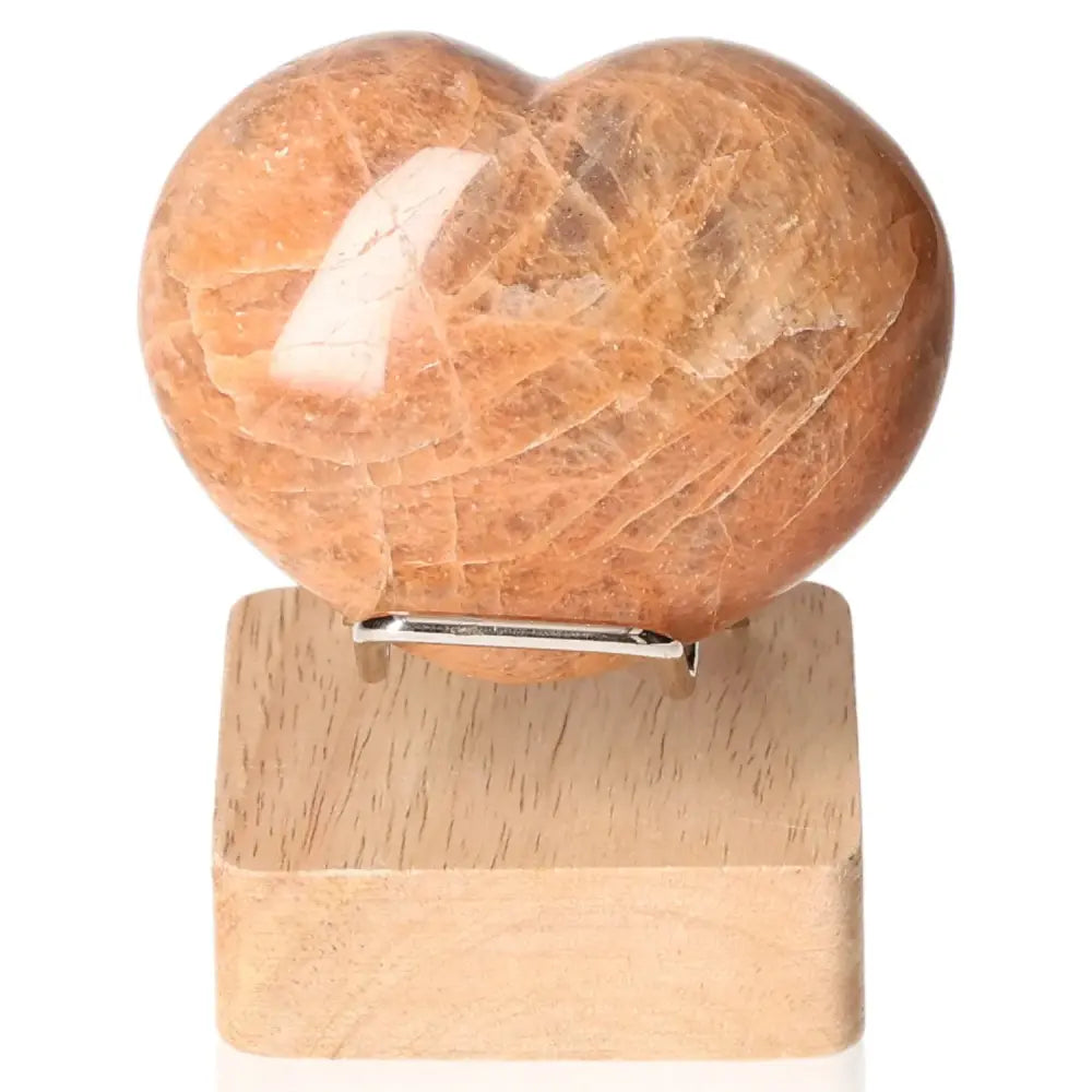 Peach Moonstone Heart on wooden stand showcasing natural stone patterns, enhancing emotional balance and intuition. Stand not included.