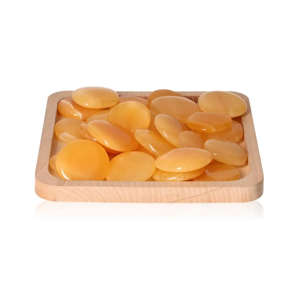 Orange Calcite Palm Stones on a wooden tray, enhancing self-confidence, motivation, and learning, ideal for energy and concentration boost.