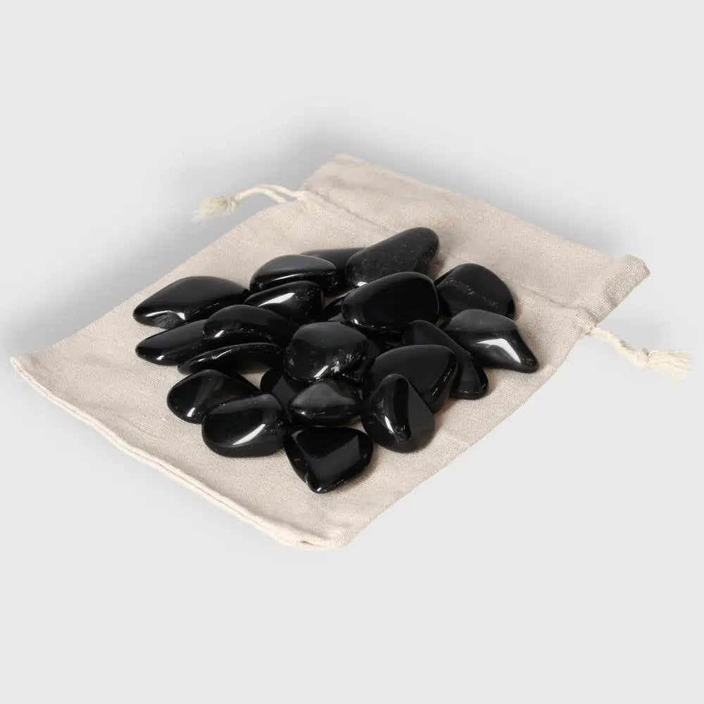 Tumbled Obsidian stones in beige pouch, known for protective energy and aura, absorbing negativity for a serene environment.
