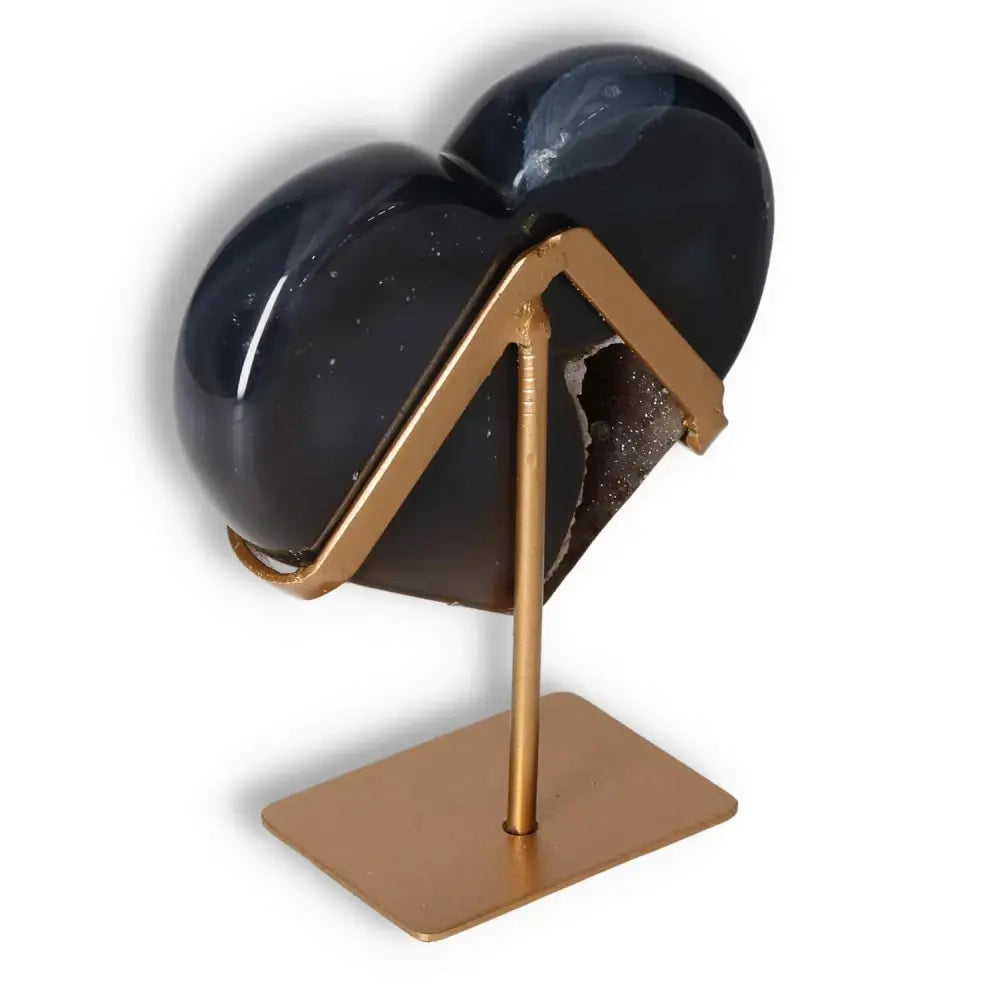 Elegant agate heart on display, symbolizing balance and harmony with unique energy properties, on a stylish gold stand.
