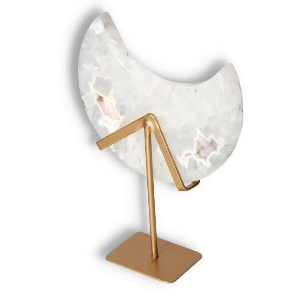 Agate lunar crescent sculpture with swirling off-white hues, featuring a golden stand, illuminating spaces with celestial elegance.