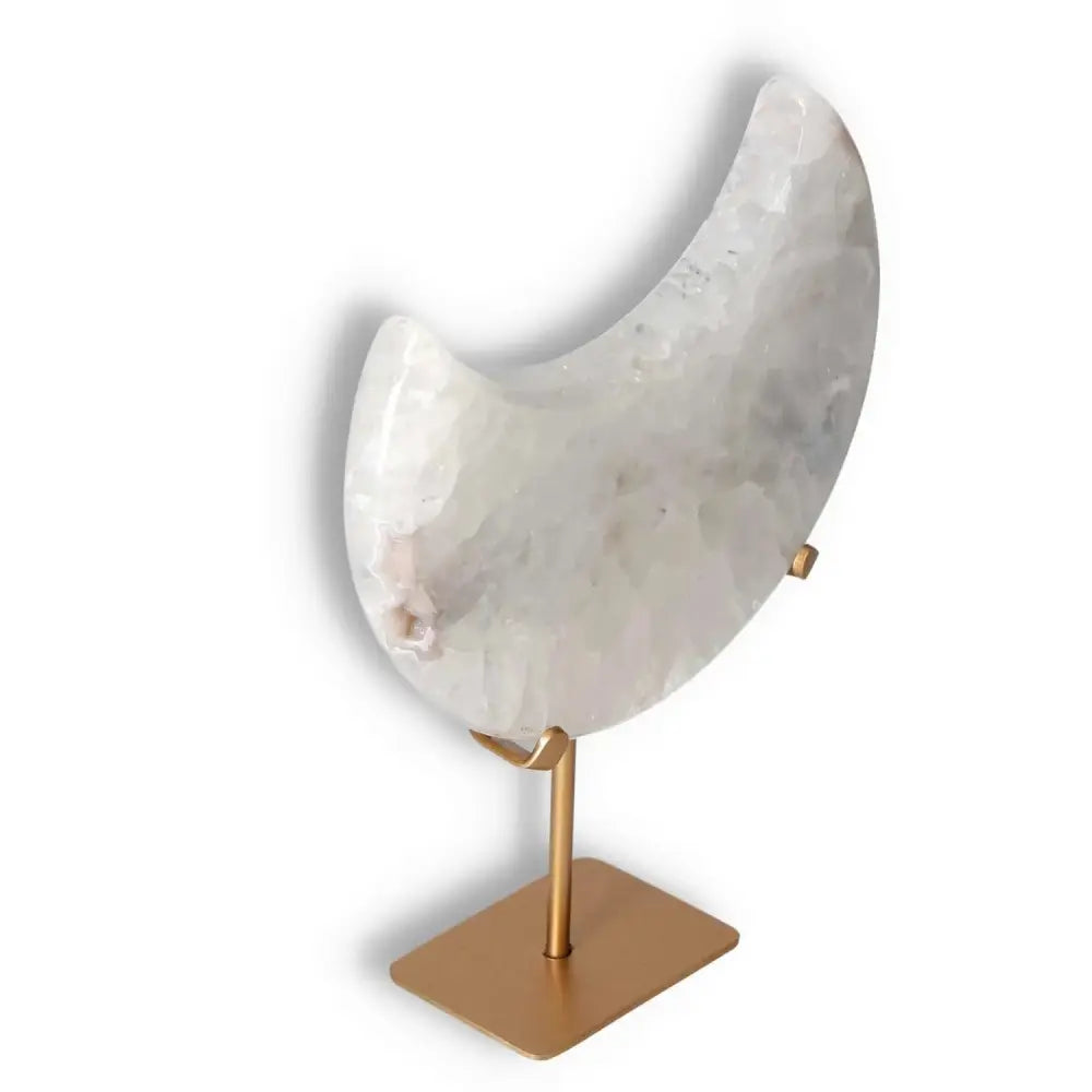 Agate lunar crescent with geode center, elegantly displayed on a stand, showcasing swirls of translucent soft white hues.